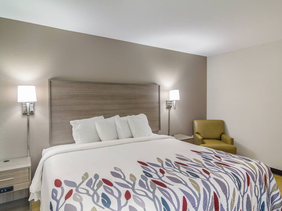 A hotel room with a bed, two bedside lamps, a chair, and a nightstand.