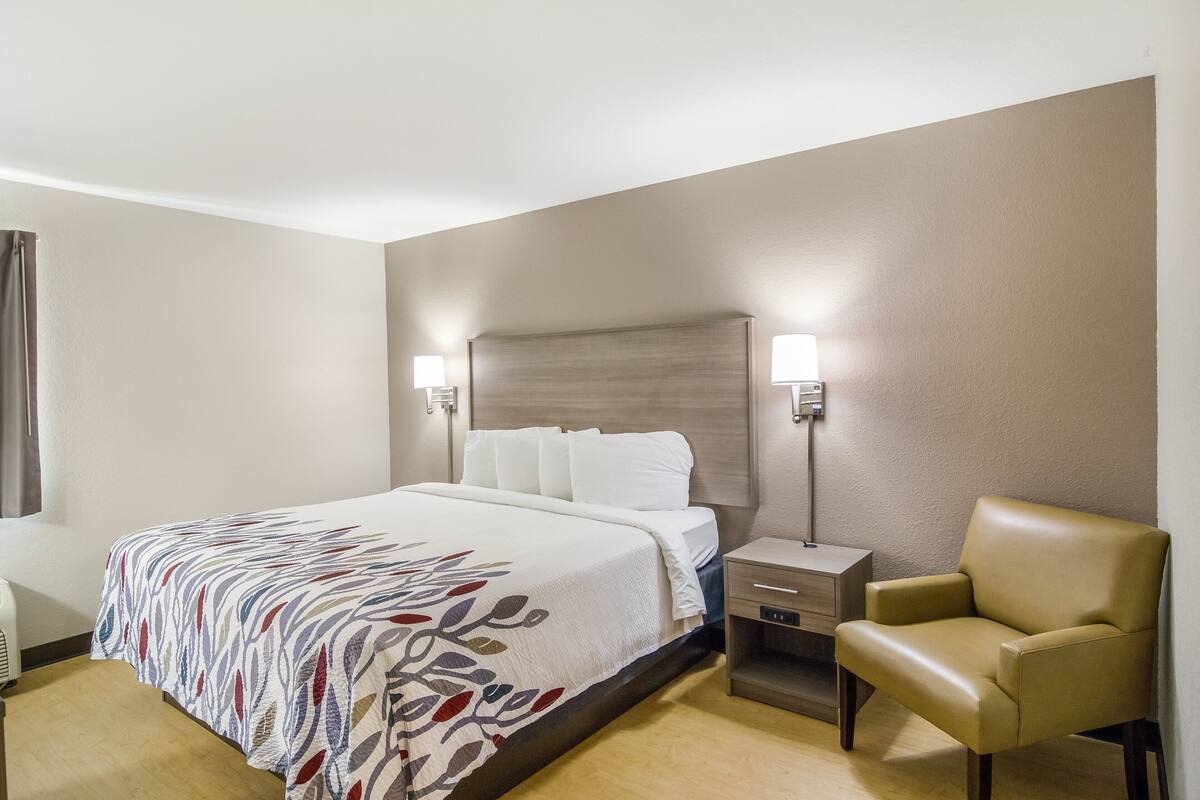 A hotel room with a bed, bedside lamps, a chair, and a nightstand.