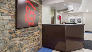 A reception desk with a stone wall backdrop and a sign that reads "Red Roof Inn."