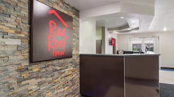 Un mostrador de recepción con un fondo de pared de piedra y un cartel que dice 'Red Roof Inn'.
