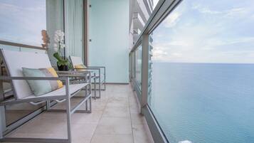 Un balcón con dos sillones, una orquídea en maceta y vista al mar.