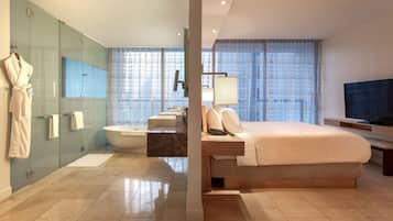 Quarto de hotel moderno com uma cama grande, banheira e área de chuveiro com paredes de vidro.