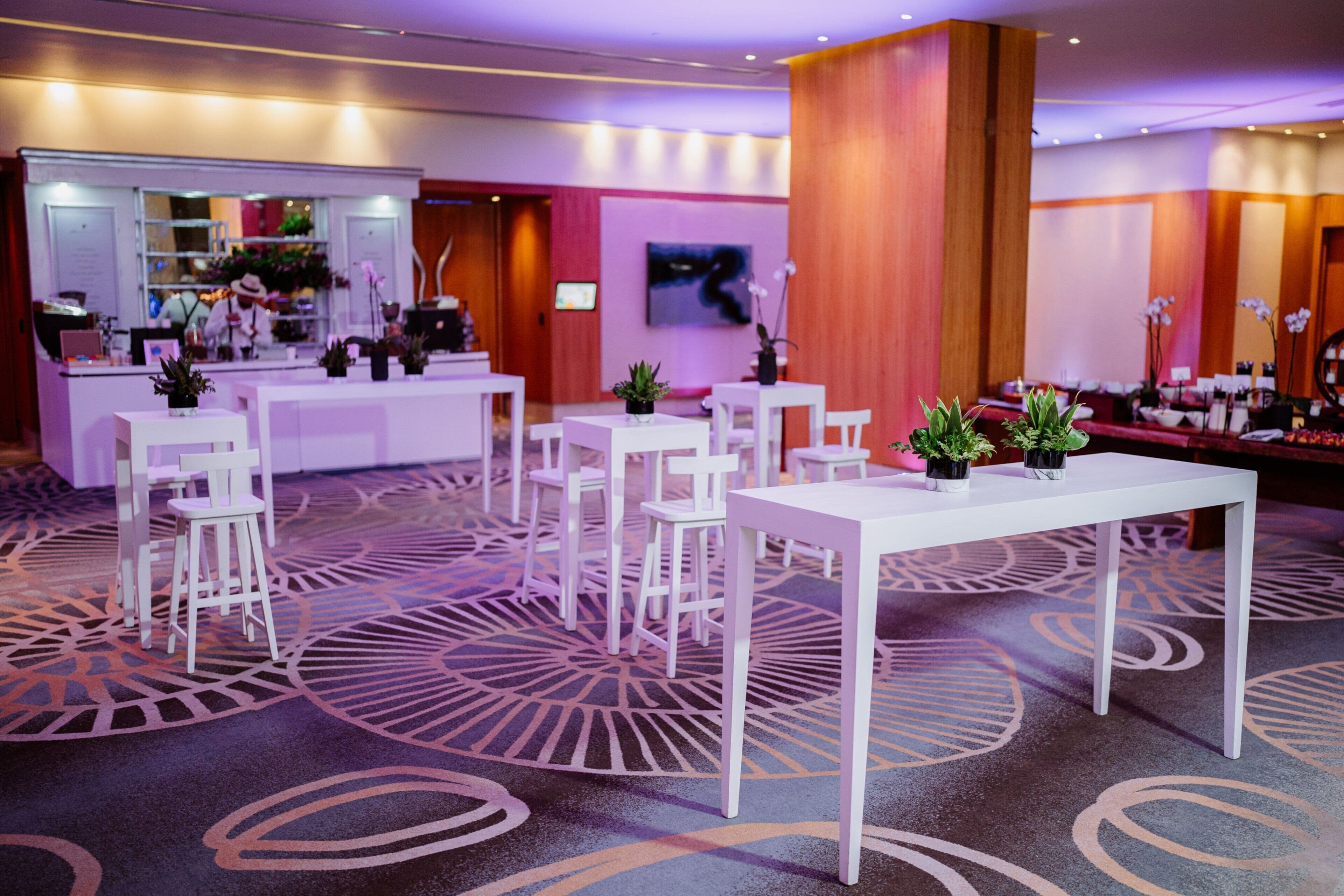 A hotel lobby with white furniture, a reception desk, and a large mirror.