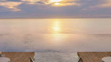 A serene outdoor seating area with a view of the sunset over the water.