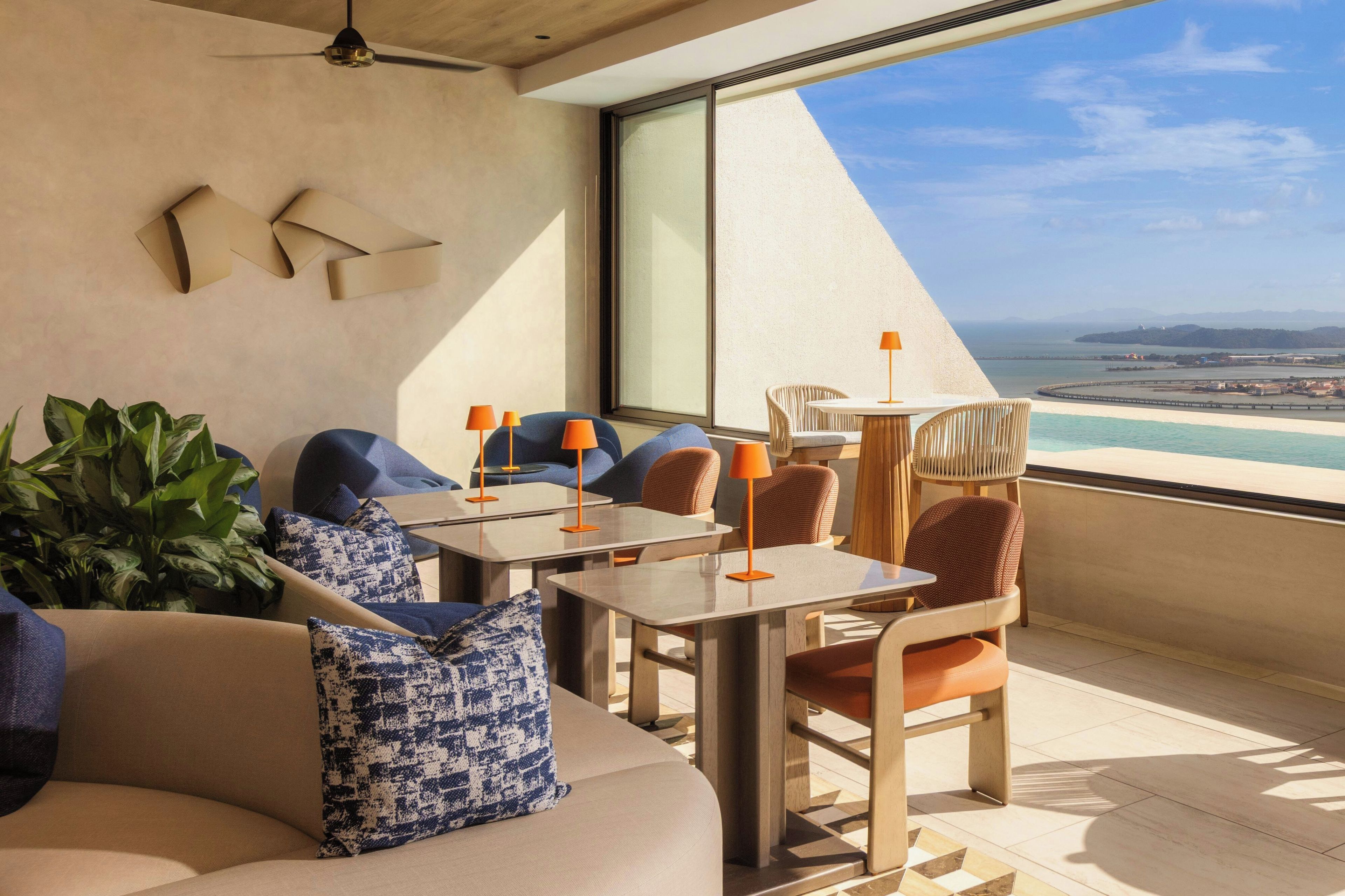Una sala de estar moderna con un sofá, sillas y una mesa, con vista al mar.