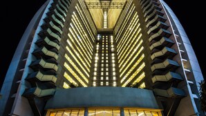 Een modern gebouw met een symmetrische gevel, meerdere balkons en een centraal atrium met verlichting.