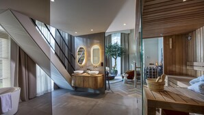 Un baño moderno con una bañera independiente, un tocador de madera y un espejo grande.