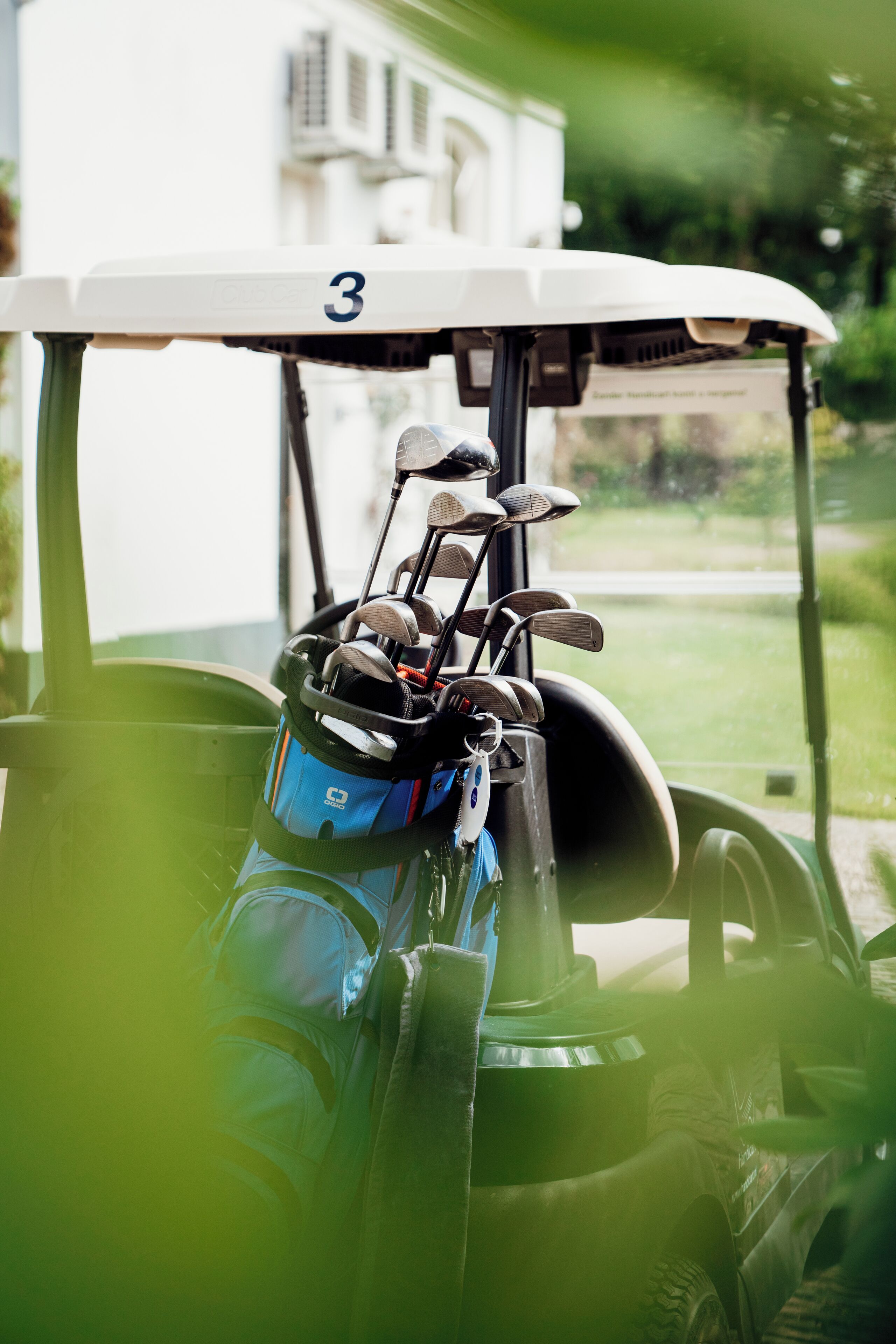 Un carrito de golf con un bolso de palos y el número 3 en el vehículo.