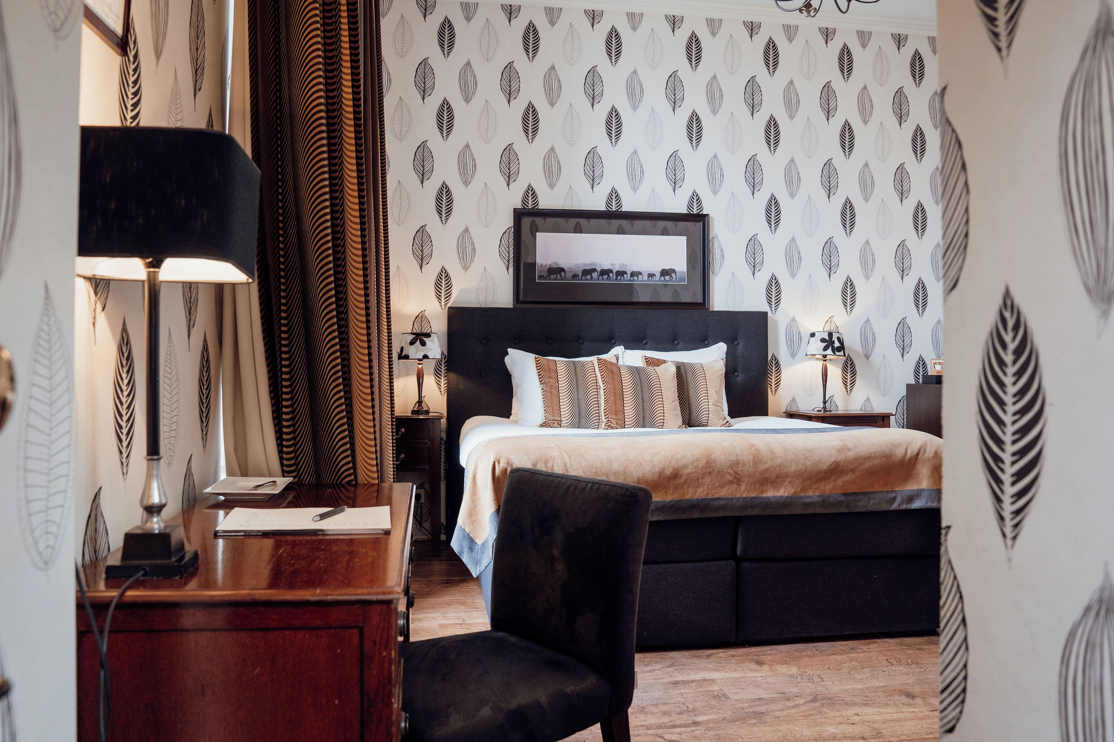 Hotelkamer met een bed, een bureau, een stoel, een lamp en een ingelijste foto aan de muur.