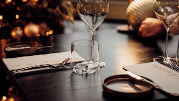 A table set with a wine glass, a small glass, a knife, a fork, and a plate.