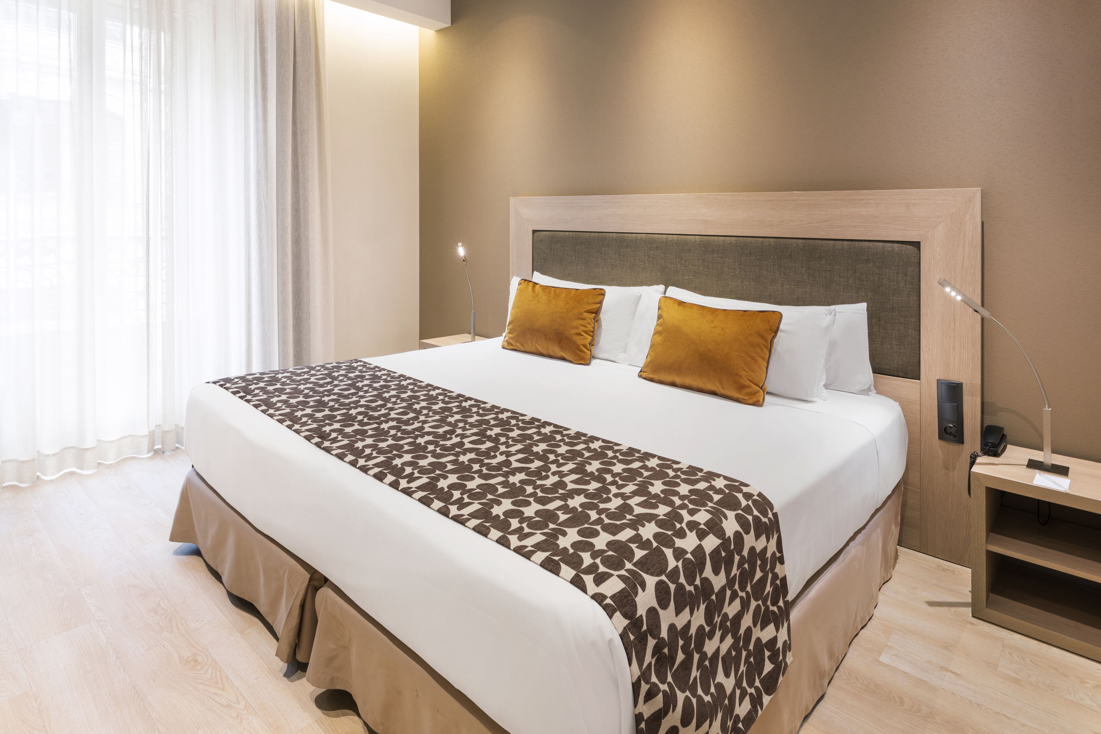 Una cama bien hecha con una colcha estampada, un cabecero de madera y dos almohadas.