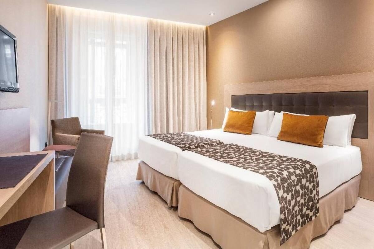 A hotel room with a bed, a desk, and a chair.