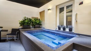 A rectangular hot tub with a tiled edge, surrounded by a stone deck and potted plants. - Catalonia Plaza Mayor (Madrid)