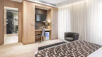 Een moderne hotelkamer met een bed, een bureau met stoel, een televisie en een douche.
