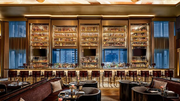 A bar area with multiple shelves of bottles, bar stools, and seating arrangements.