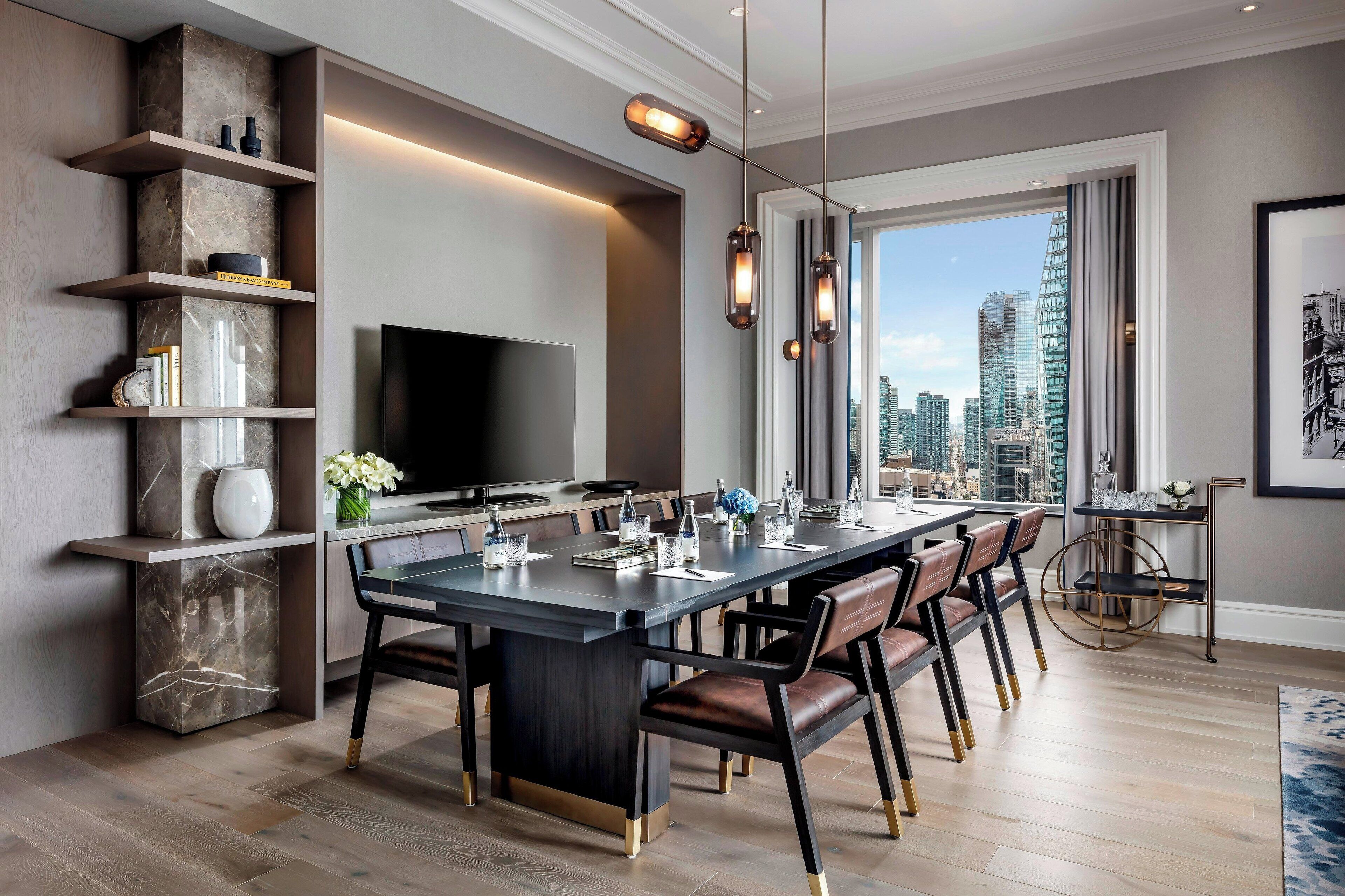 Uma sala de jantar moderna com uma mesa grande, cadeiras e vista para a cidade.