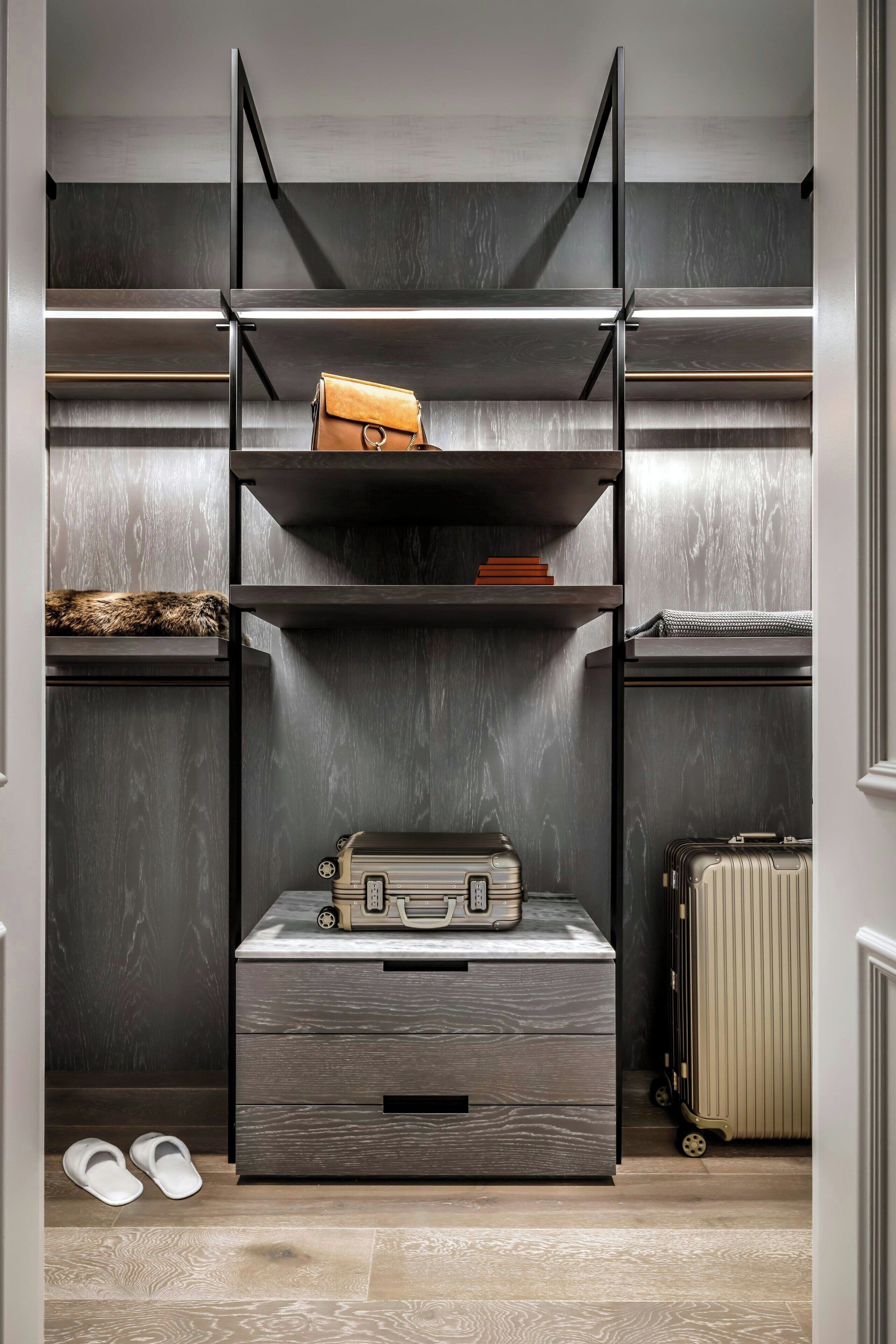 A storage unit with multiple shelves and drawers, a suitcase, and a pair of slippers.