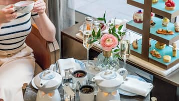 A table set for a tea service with teapots, cups, and a floral arrangement.