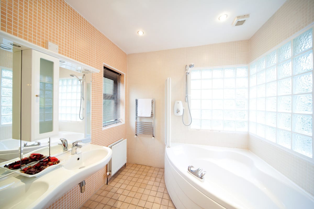 A bathroom with a sink, mirror, and bathtub.