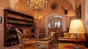 Una biblioteca con estanterías, una araña y muebles antiguos.