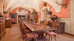 Una larga mesa de comedor con sillas, una araña y monturas de animales en las paredes.