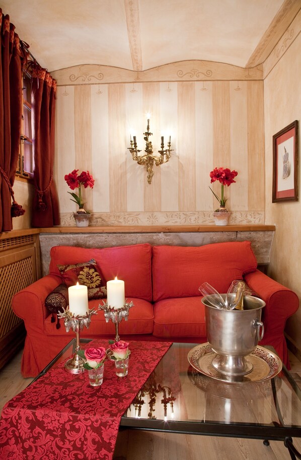 A cozy living room with a red sofa, a glass coffee table, and decorative items including candles and flowers.
