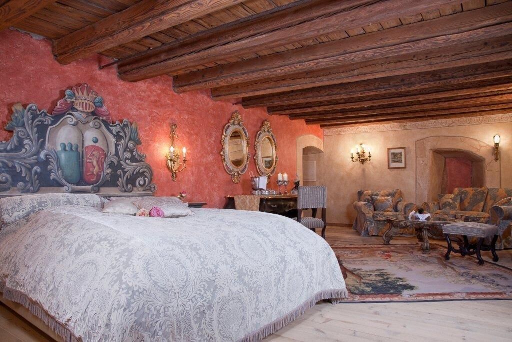 A bedroom with a large bed, ornate wall decor, and a classic wooden ceiling.