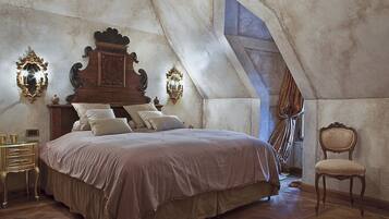 Um quarto com uma cama grande, cabeceira ornamentada e um lustre.