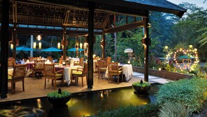 An outdoor dining area with tables and chairs, a water feature, and a decorative arch. - The Samaya Ubud (Ubud)