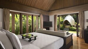A spacious bedroom with a large bed, a TV, and a view of a garden through large windows. - The Samaya Ubud (Ubud)