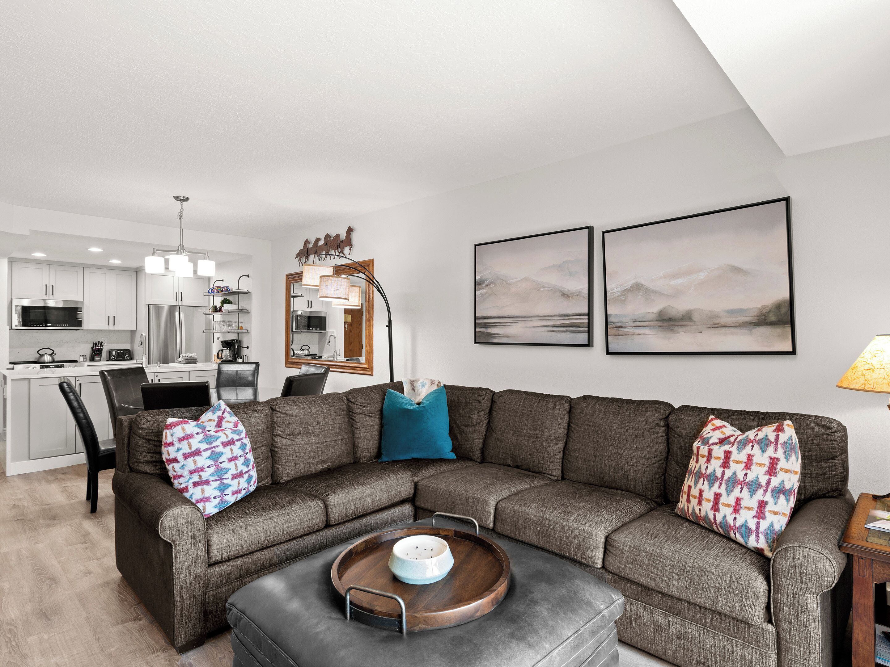 Una sala de estar moderna con un sofá modular, un comedor y una cocina al fondo.