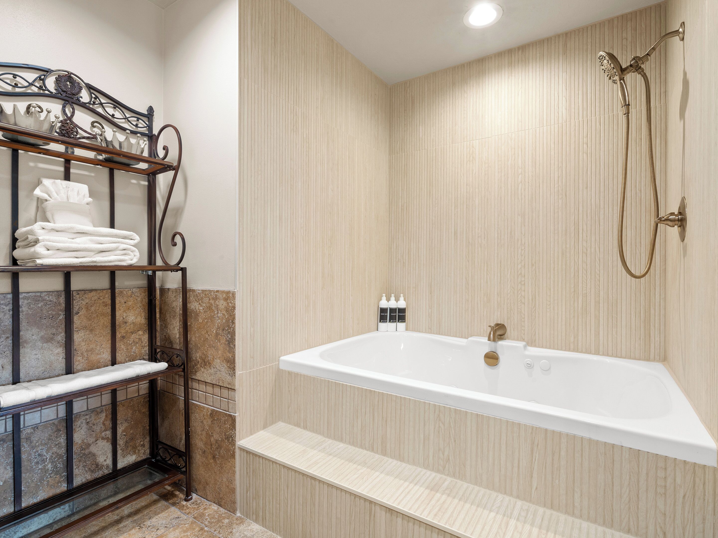 A modern bathroom with a freestanding bathtub, a showerhead, and a towel rack with folded towels.