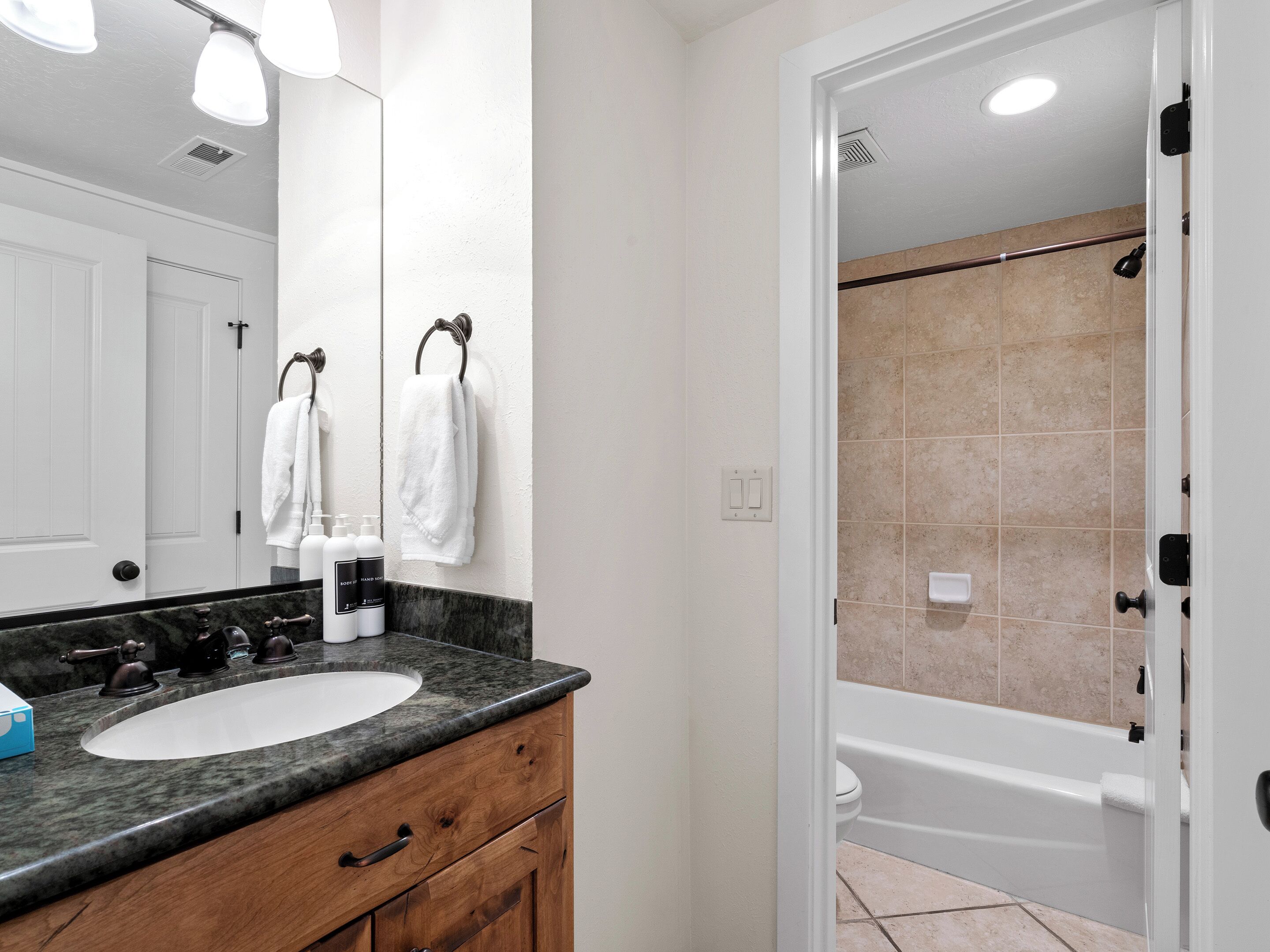 A bathroom with a double sink vanity, a large mirror, and a shower area.