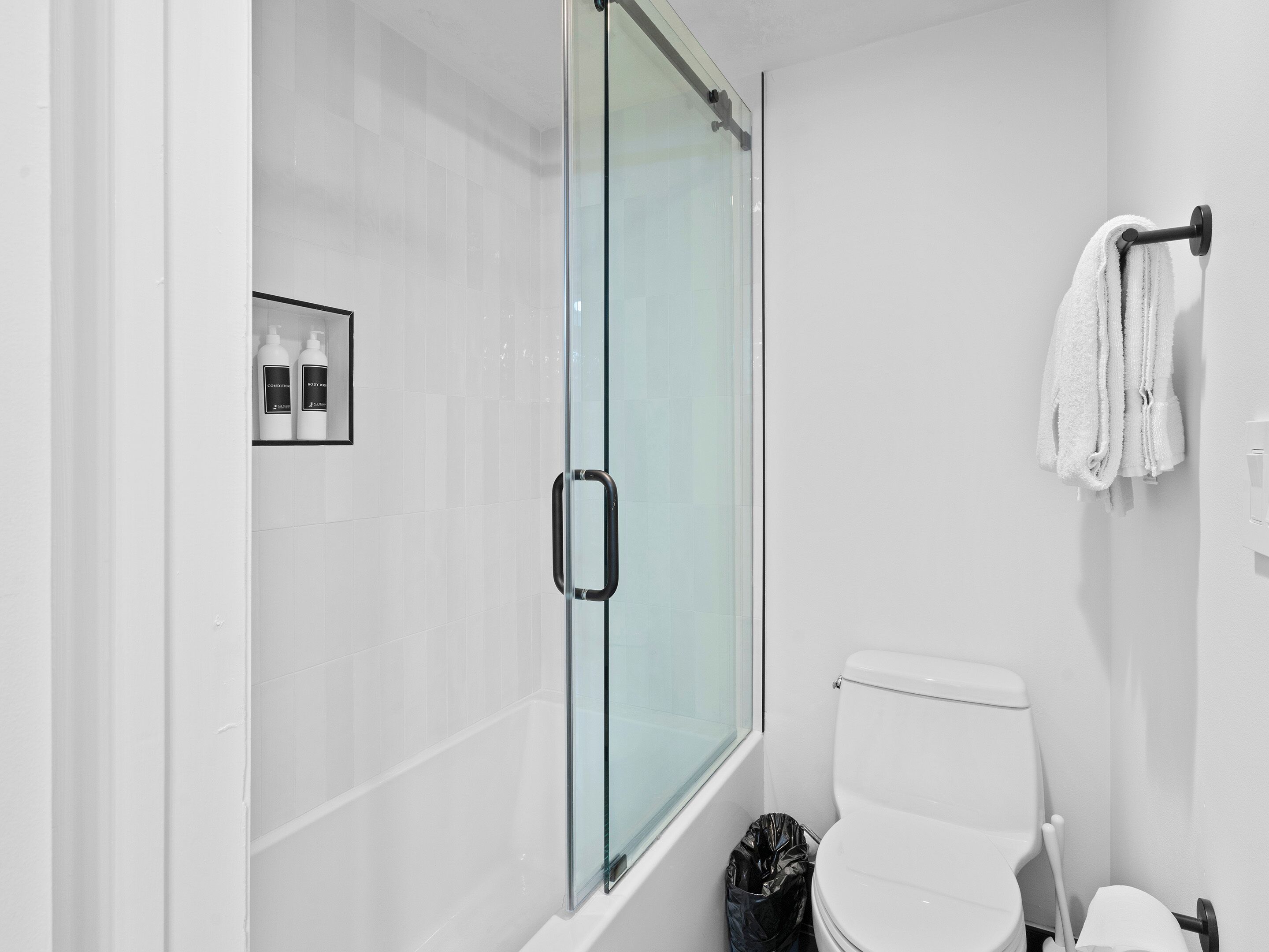 A modern bathroom with a glass shower enclosure, a toilet, and a towel rack.