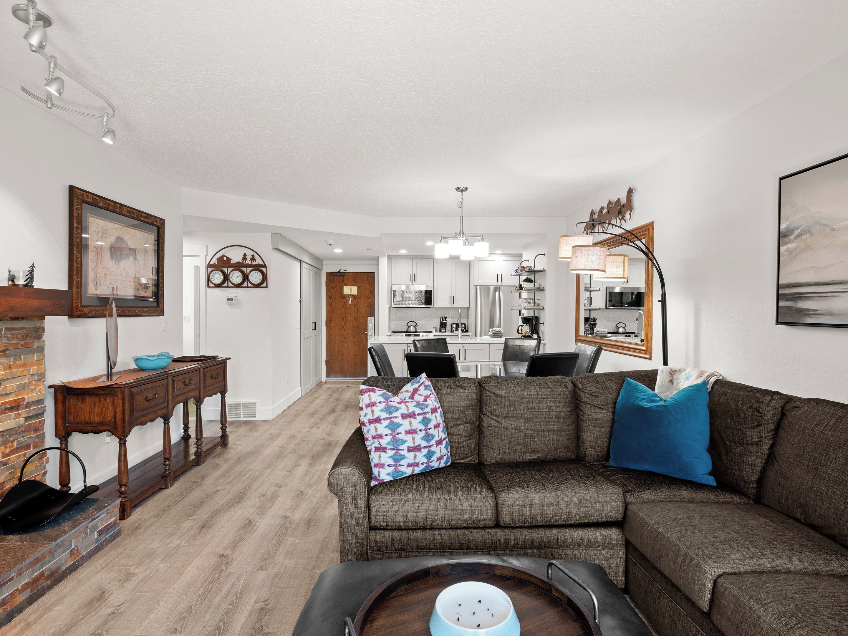 A modern living room with a sectional sofa, a dining area, and a kitchen in the background.