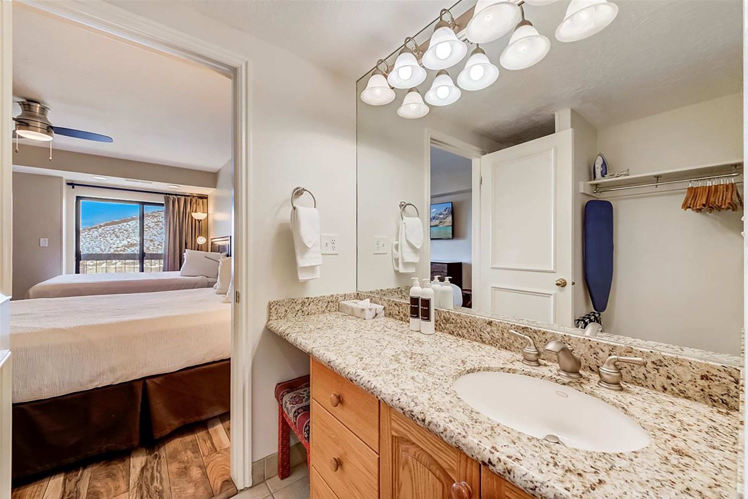 A modern bathroom with a large mirror, granite countertop, and a double sink.