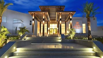 Um edifício moderno com entrada coberta, degraus que levam a ele e uma placa com a inscrição 'Jaz Casa Del Mar Beach'.