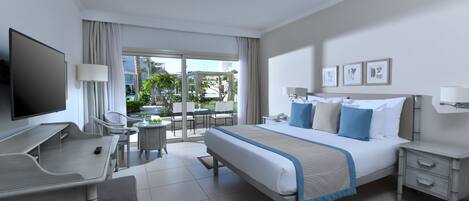 Ein Hotelzimmer mit Bett, Schreibtisch, Stuhl, Fernseher und einem Balkon mit Sitzgelegenheit.