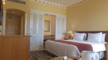 A hotel room with a bed, a nightstand, a lamp, a mirror, and a wardrobe with louvered doors.