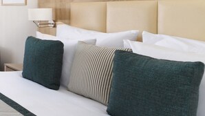A hotel room with a large bed, multiple pillows, a headboard, a bedside table with a lamp, and framed botanical artwork on the wall. - JAZ Elite Casa Del Mar Beach - All inclusive (Hurghada)