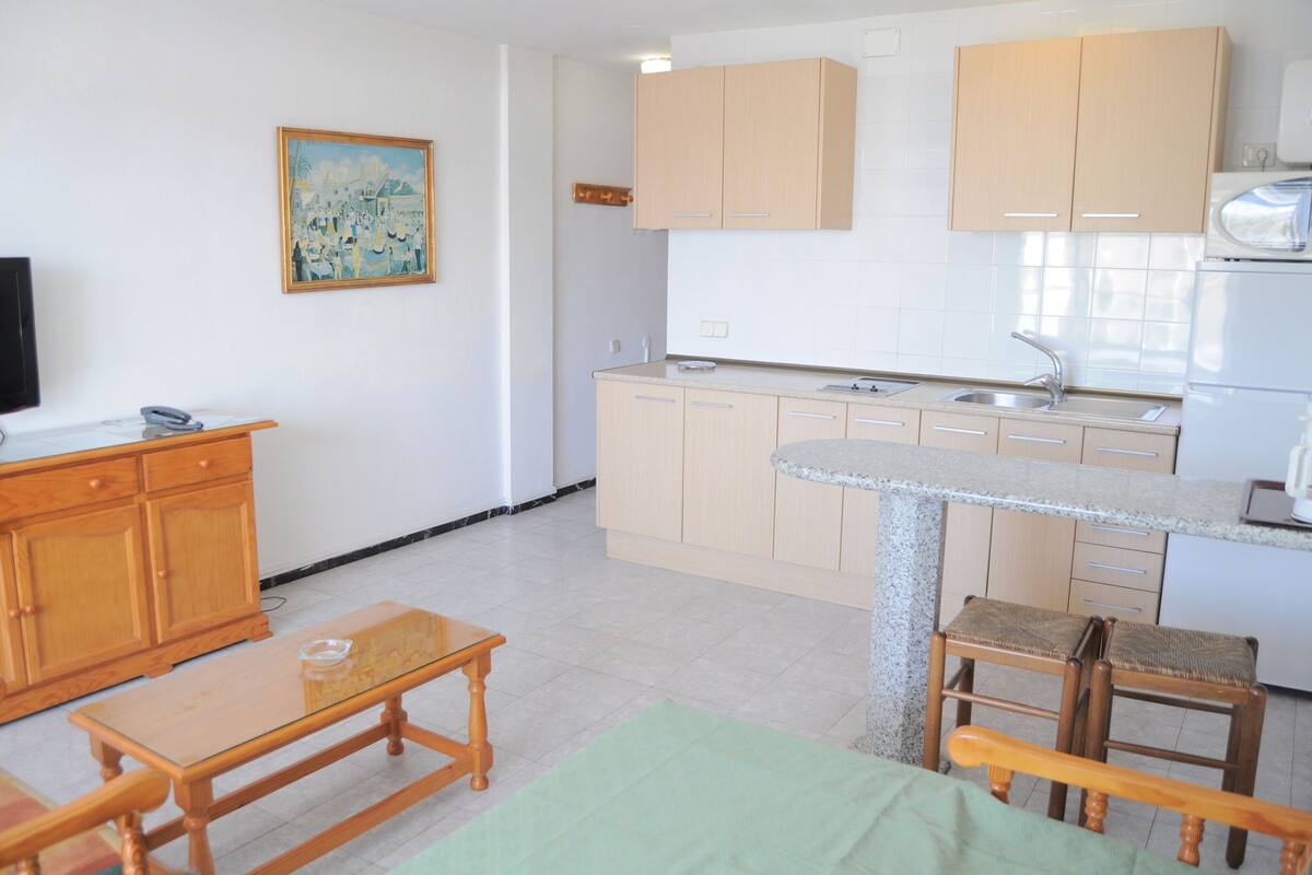 A compact kitchen with wooden cabinets, a granite countertop, and a built-in stove.