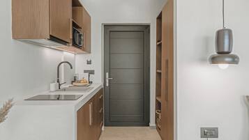 A modern kitchen with a white countertop, wooden cabinets, and a dark door.