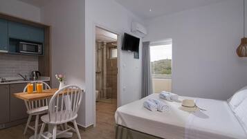Habitación de hotel con cama, escritorio, silla, televisión y vistas al exterior.
