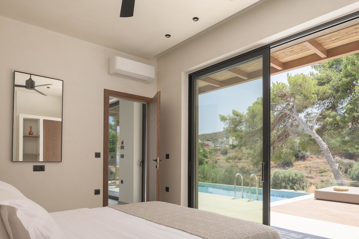 A bedroom with a large bed, a ceiling fan, a mirror, and a sliding glass door leading to an outdoor pool area.