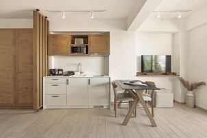 A modern kitchen with wooden cabinets, a microwave, and a dining area with a table and chairs.