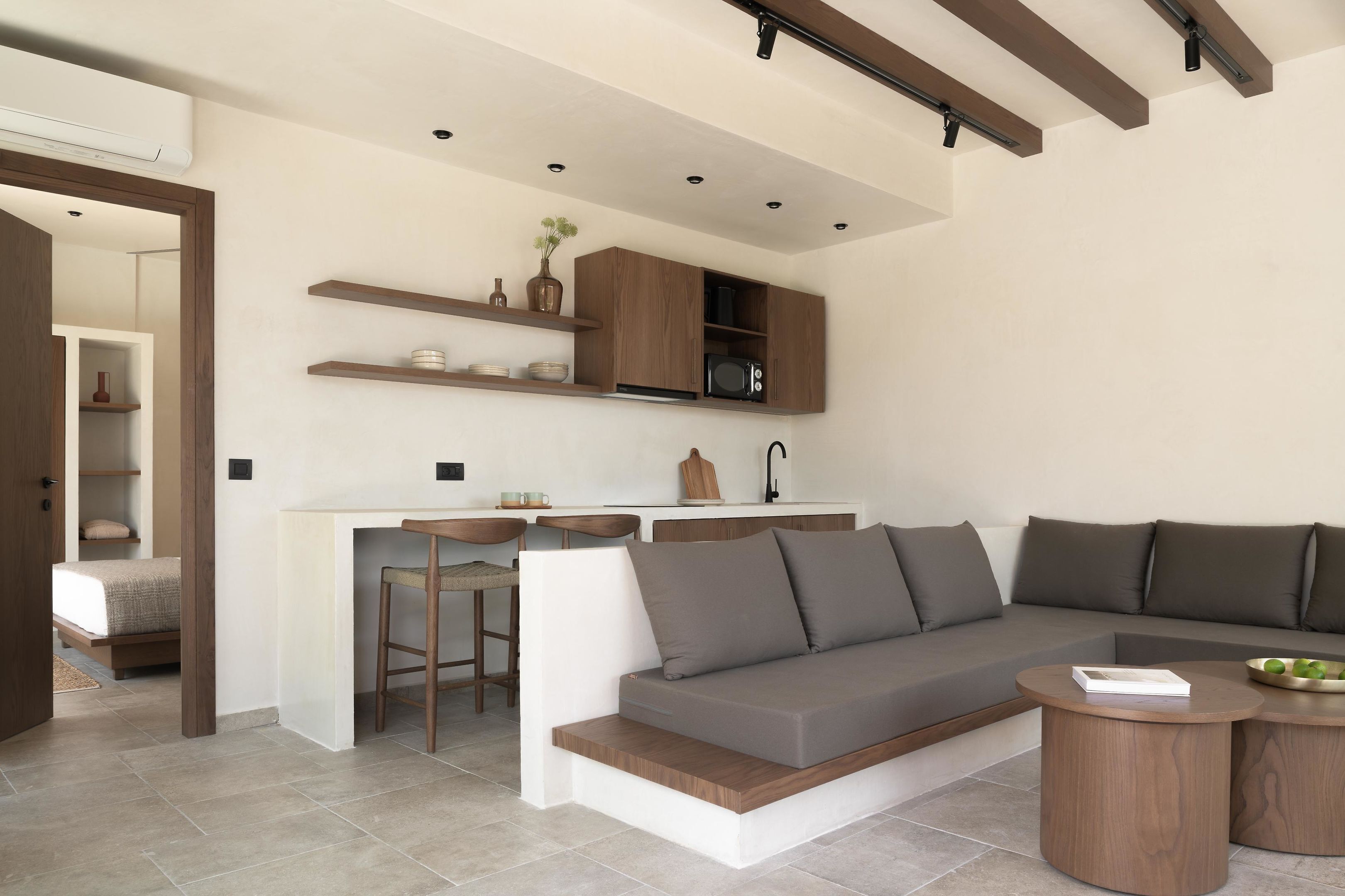 A modern living space with a built-in kitchen, a sofa, and a small dining area.