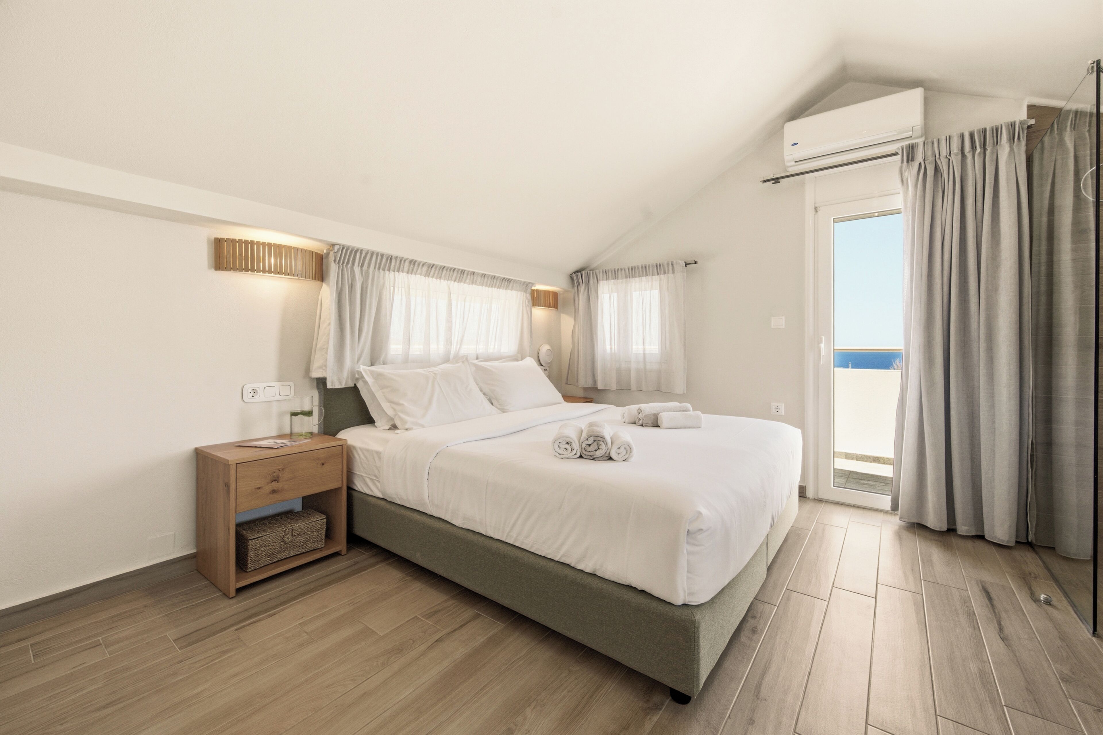 Une chambre à coucher avec un lit, une table de chevet et une vue sur l’extérieur.