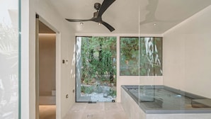 Uma casa de banho moderna com chuveiro em cabine de vidro, uma banheira independente e um ventilador de teto.