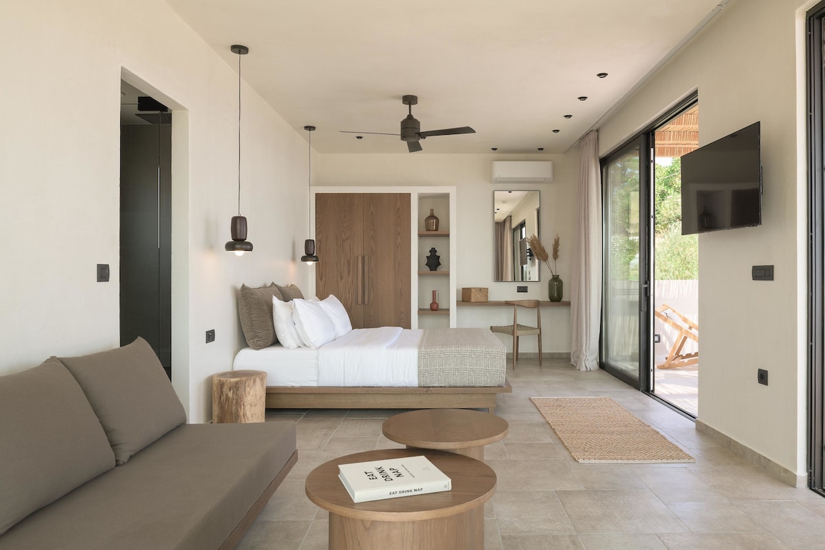 A modern bedroom with a bed, a sofa, a desk, and a TV.