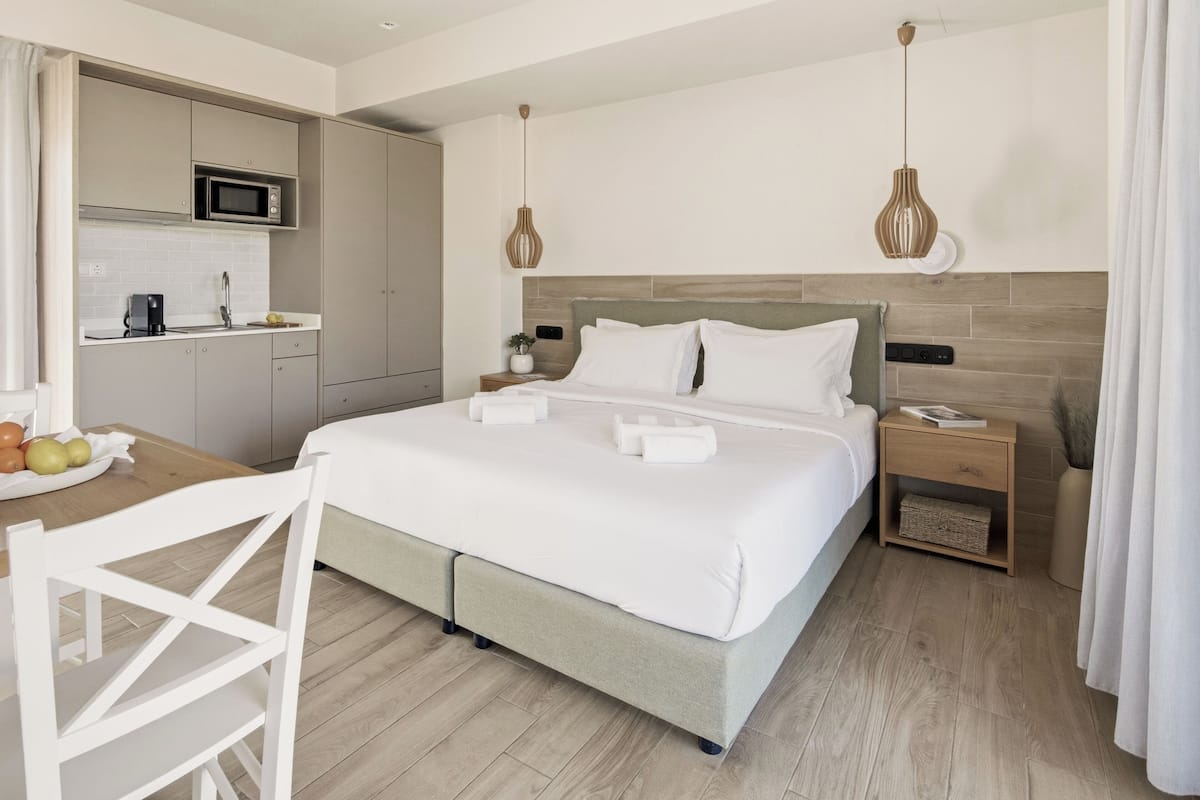 A hotel room with a bed, bedside table, and a kitchenette area.